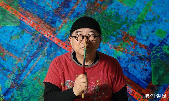 화가로 변신한 가수 김수철이 2일 오전 서울 중랑구 본인의 작업실에서 소리를 시각적으로 재구성한 작품들을 배경으로 포즈를 취하고 있다. 이한결 기자 always@donga.com