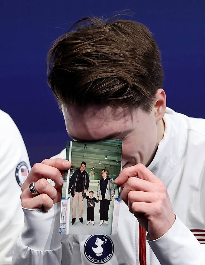 미국 피겨스케이팅 맥심 나우모프가 10일 이탈리아 밀라노 밀라노 아이스 스케이팅 아레나에서 열린 2026 밀라노·코르티나담페초 동계올림픽 남자 싱글 쇼트프로그램 연기를 마친 뒤 부모의 사진을 들어 보이며 울고 있다. 로이터