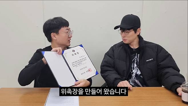 충주맨 김선태(사진 왼쪽) 주무관이 배우 박정민에게 홍보대사 위촉장을 건네고 있는 '충TV' 영상 캡처 사진.(충주시 제공)