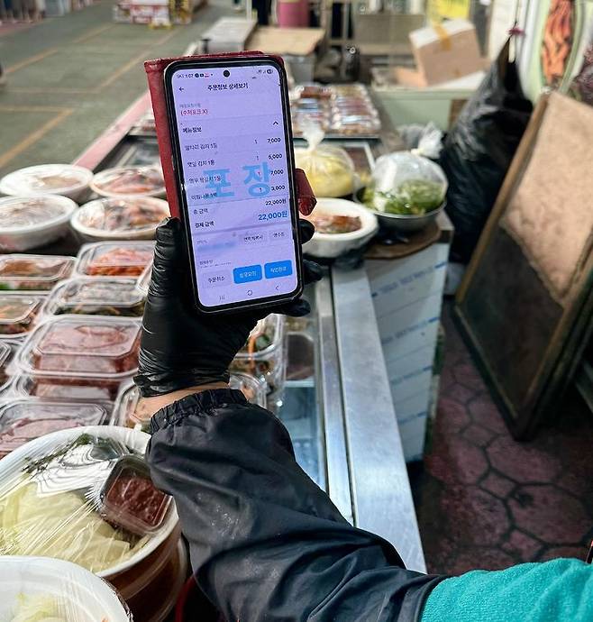 [대구=뉴시스] 정재익 기자 = 12일 대구 달서구 달서시장에서 한 반찬가게 상인이 휴대전화 앱을 통해 주문 접수를 받고 있다. 2026.02.12. jjikk@newsis.com *재판매 및 DB 금지