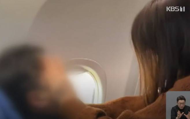 항공기 기내에서 경련을 일으킨 남성 승객에게 응급조치를 시행하고 있는 여성 승객. (사진=KBS 보도 캡처)