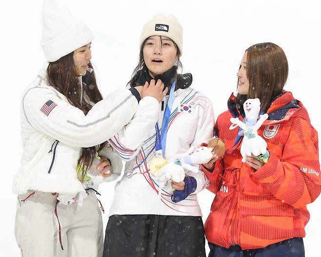 12일(현지시간) 이탈리아 리비뇨 스노파크에서 열린 2026 밀라노·코르티나담페초 동계 올림픽 스키 스노보드 여자 하프파이프 결선에서 은메달을 획득한 미국의 클로이 김이 금메달을 획득한 최가온의 옷 매무새를 고쳐주고 있다. 연합뉴스