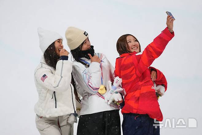 [리비뇨=AP/뉴시스] 최가온(가운데)이 12일(현지 시간) 이탈리아 리비뇨 스노파크에서 열린 2026 밀라노·코르티나담페초 동계올림픽 스노보드 여자 하프파이프 정상에 올라 은동메달 수상자와 셀카를 찍고 있다. 최가온은 1차 시기에서 크게 넘어져 충격을 안겼으나 3차 시기에서 90.25점을 획득해 강력한 우승 후보 클로이 김(미국, 왼쪽)을 제치고 금메달을 목에 걸었다. 최연소 금메달 기록도 갈아치운 그는 시상식 도중 애국가가 흘러나오자, 끝내 눈물을 흘렸다. 2026.02.13.