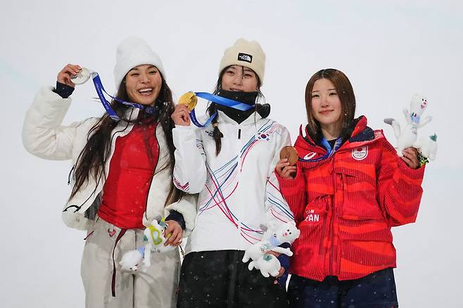 [리비뇨=AP/뉴시스] 최가온(가운데)이 12일(현지 시간) 이탈리아 리비뇨 스노파크에서 열린 2026 밀라노·코르티나담페초 동계올림픽 스노보드 여자 하프파이프 정상에 올라 금메달을 들고 포즈를 취하고 있다. 최가온은 1차 시기에서 크게 넘어져 충격을 안겼으나 3차 시기에서 90.25점을 획득해 강력한 우승 후보 클로이 김(미국, 왼쪽)을 제치고 금메달을 목에 걸었다. 최연소 금메달 기록도 갈아치운 그는 시상식 도중 애국가가 흘러나오자, 끝내 눈물을 흘렸다. 2026.02.13.