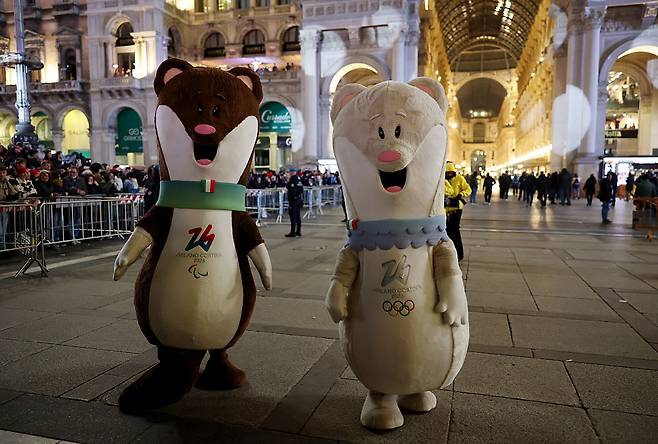 지난 6일 이탈리아 밀라노에서 열린 성화 봉송 행사에서 밀라노-코르티나 2026 동계올림픽 마스코트인 티나와 밀로의 탈을 뒤집어 쓴 연기자들이 자리하고 있다. [게티이미지]