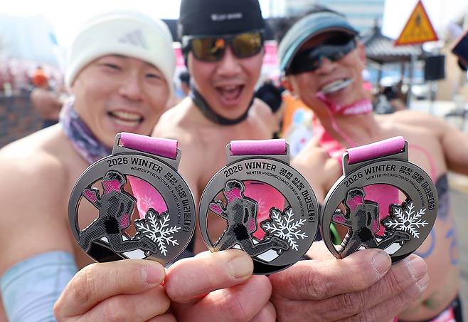 Participants at the Pyeongchang Daegwallyeong Naked Marathon hold up their medals on Saturday after completeing the race. (Newsis)