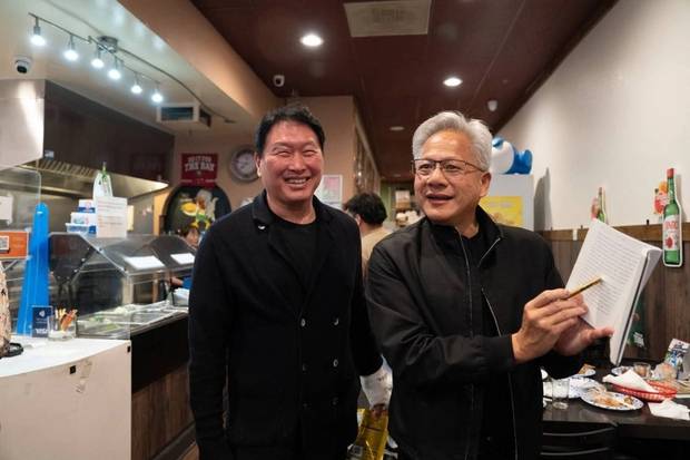 지난 5일(현지시간) 미국 캘리포니아 산타클라라의 한 한국식 호프집에서 최태원 SK그룹 회장과의 만난 젠슨 황 엔비디아 CEO가 신간 ‘슈퍼모멘텀’을 펼쳐보이고 있다. / 연합뉴스