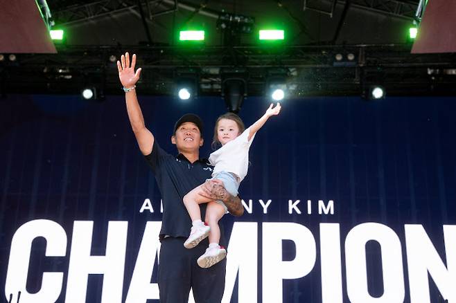 앤서니 김이 LIV 골프 애들레이드에서 우승한 뒤 딸을 안고 시상대에 올라 손을 들어 인사하고 있다. (사진=LIV Golf)