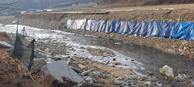 지난해 7월 극한 호우가 내려 제방과 도로가 쓸려내려간 곳에 임시로 복구한 뒤 천막을 쳐 놓았다.