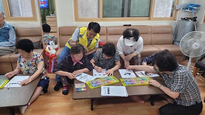 성정모 스마트 매니저(뒷줄 중앙)가 대전 유성구 장대경로당에서 그림책에 색칠하는 법을 설명하고 있다. 유성구노인복지관 제공