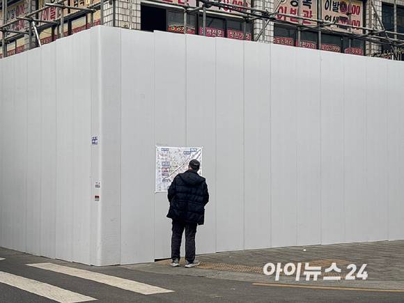 2월 10일 철거현장에서 한 시민이 공사도를 유심히 보고있다. [사진=김민지 기자]