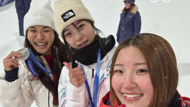 최가온(가운데)이 13일 스노보드 여자 하프파이프 시상대에서 금메달을 목에 걸고 은메달을 딴 미국의 클로이 김(왼쪽)과 동메달리스트 일본의 오노 미쓰키와 밝은 표정으로 셀카를 찍고 있다./삼성전자