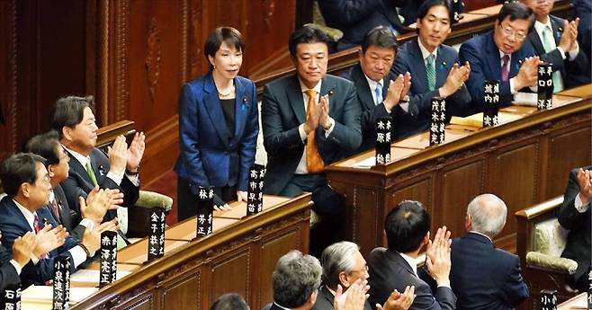 < 공고해진 다카이치 시대 > 일본 첫 여성 총리이자 집권 자민당 총재인 다카이치 사나에 총리가 18일 소집된 특별의회 총리 지명선거에서 승리해 총리로 재선출됐다. 다카이치 총리는 이날 중의원 투표 총수 464표 중 354표를 획득해 압도적인 과반을 확보했다. 결선 투표 결과가 발표된 뒤 다카이치 총리(왼쪽 네 번째)가 중의원 의원들에게 박수를 받고 있다.   /AFP연합뉴스