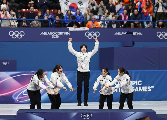 18일 이탈리아 밀라노 아이스스케이팅 아레나에서 열린 2026 밀라노-코르티나담페초 동계올림픽 쇼트트랙 여자 3000m 계주 결승에서 금메달을 따낸 한국 선수들이 시상대에 오른 모습. 나머지 선수들이 가운데 이소연 선수를 빛내주고 있다. [연합]