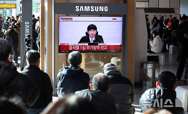 [서울=뉴시스] 이영환 기자 = 19일 오후 서울 용산구 서울역에서 시민들이 '내란 우두머리 혐의' 윤석열 전 대통령의 1심 선고 공판 중계를 시청하고 있다. 윤 전 대통령은 1심에서 무기징역을 선고 받았다. 2026.02.19. 20hwan@newsis.com