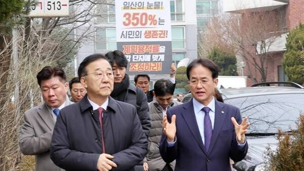 김윤덕 국토교통부 장관(사진 왼쪽)이 이동환 고양시장과 일산신도시 선도지구 정비사업 현장을 둘러보고 있는 가운데 오준환 도의원이 피켓을 들고 용적률 상향을 요구하고 있다. 오준환 도의원 사회관계망서비스(SNS) 캡처