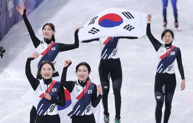 대한민국 여자 쇼트트랙 대표팀이 18일(현지시간) 이탈리아 밀라노 아이스스케이팅 아레나에서 열린 2026 밀라노·코르티나담페초 동계올림픽 쇼트트랙 여자 3000m 계주 결승에서 금메달을 차지한 후 태극기를 두르고 관중석을 향해 인사하고 있다. 밀라노=뉴스1