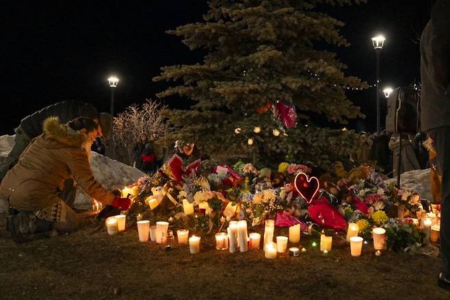 11일(현지시간) 캐나다 브리티시컬럼비아주 텀블러리지의 작은 마을에서 한 주민이 전날 발생한 총기 난사 사건 희생자들을 추모하는 촛불 추모식에서 추모비에 꽃을 놓고 있다.AFP연합뉴스