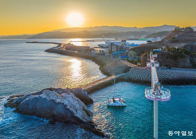 경북 울진 후포항에서 출발한 요트 승객들이 노을이 지는 바다에서 등기산 스카이워크와 갓바위를 감상하고 있다.