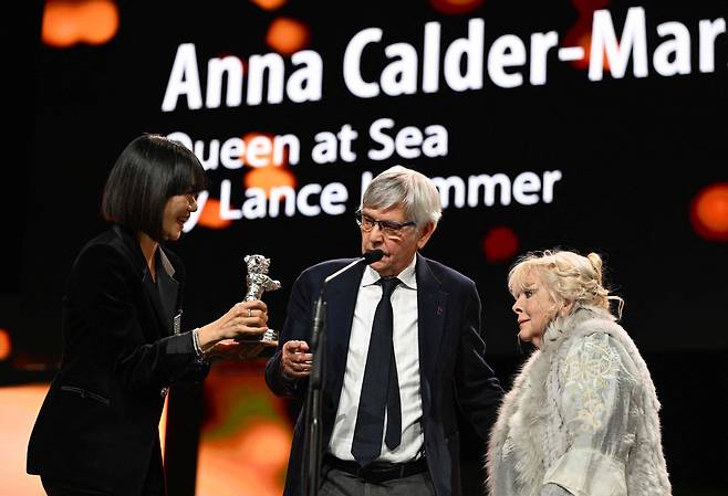 21일(현지시각) 개최된 제76회 베를린국제영화제 시상식에서 심사위원인 배두나가 조연상을 공동 수상한 영화 '퀸 앳 시(Queen at Sea)'의 배우 톰 코트니와 애나 콜더 마셜에게 트로피를 건네주고 있다./AFP연합뉴스