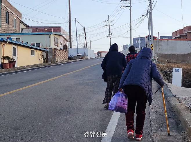 석리마을 주민들이 지난 2월 9일 언덕 위에 있는 임시 주거용 조립주택 단지로 걸어가고 있다. 해안 절벽에 자리잡은 석리마을 주택들은 지난해 3월 산불로 대부분 전소됐고, 절벽 위 능선을 따라 지어진 주택들만 일부 남아있다. 이재덕 기자