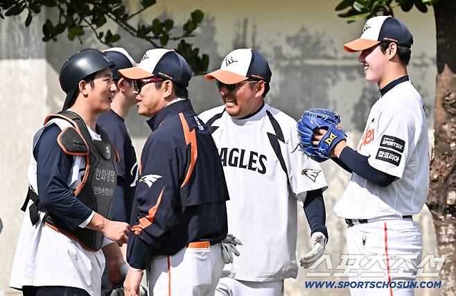 불펜 피칭을 마친 뒤 포수 최재훈과 양상문 코치가 문동주와 대화를 나누며 미소 짓고 있다.