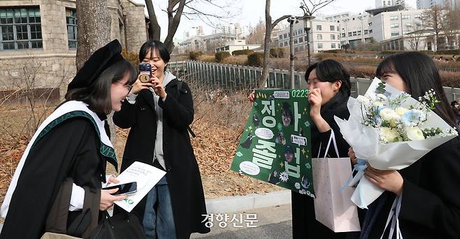 한 졸업생이 학우들이 만들어준 현수막을 바라보며 웃음 짓고 있다.