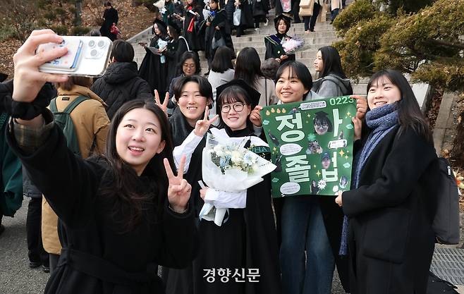 졸업생이 학우들이 만들어준 현수막과 함께 기념사진을 찍고 있다.