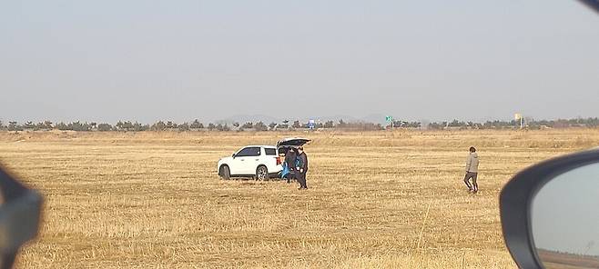 차 트렁크에서 동물 사체가 담긴 것으로 추정되는 비닐봉투를 꺼내 들고 있는 사람들. (사진 제보자 제공)/뉴스펭귄