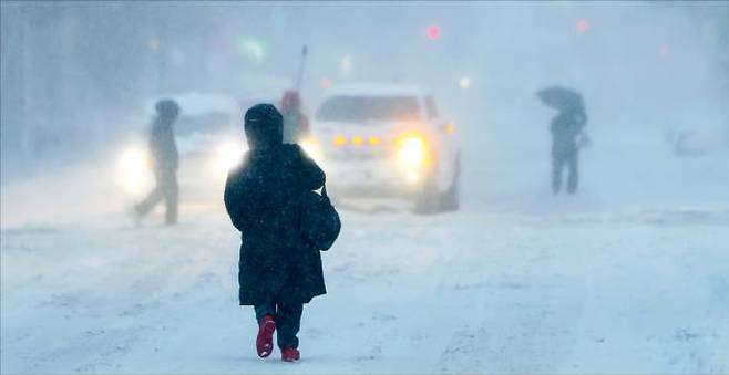 23일 미국 뉴욕 브루클린에 눈보라가 몰아치는 가운데 시민들이 눈으로 뒤덮인 거리를 걷고 있다. 뉴욕시는 이날 대규모 눈폭풍에 대비해 차량 운행을 통제하고 학교에 휴교령을 내렸다. AFP연합뉴스