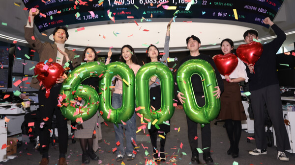 코스피가 사상 처음으로 6,000을 돌파해 거래를 마친 25일 서울 중구 하나은행 딜링룸에서 딜러들이 기념 세리머니를 하고 있다. 연합뉴스