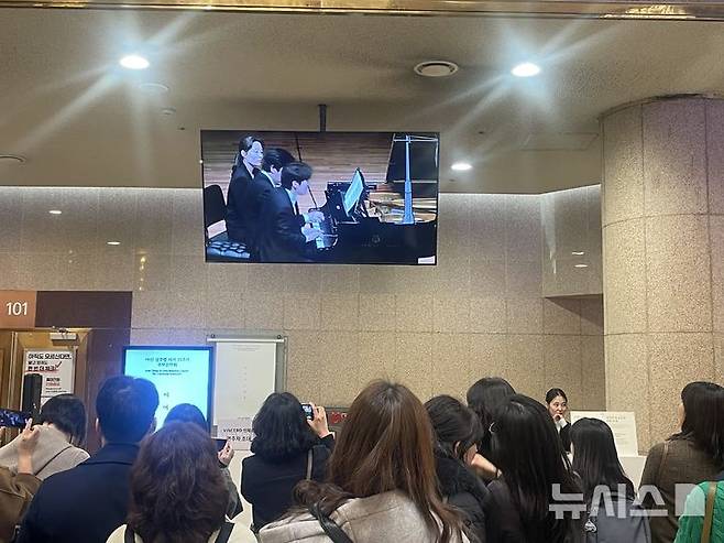 [서울=뉴시스] 류인선 기자 = 피아니스트 김선욱과 조성진이 25일 서울 서초구 예술의 전당에서 열린 고(故) 정주영 창업회장 추모 음악회에서 공연하는 모습을 시민들이 모니터를 통해 시청하고 있다. 2026.2.25. photo@newsis.com