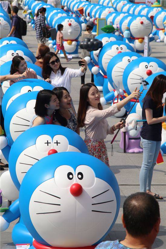 28일, 용산 아이파크몰 광장에서 시민들이 일렬로 늘어선 대형 도라에몽 모형을 보며 즐거워하고 있다.
