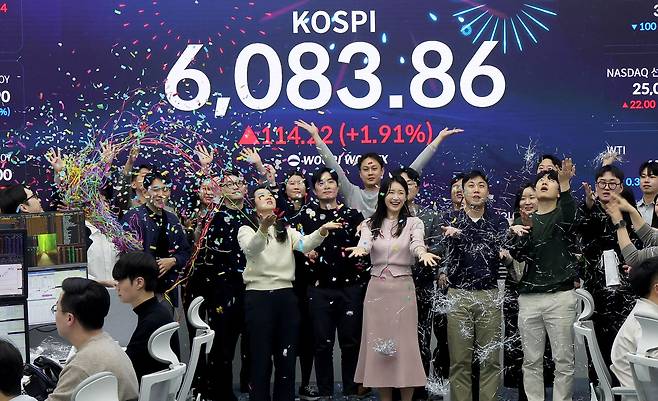코스피가 사상 처음 6000선을 돌파해 6083.86으로 장을 마친 25일 서울 중구 우리은행 본점 딜링룸에서 직원들이 환호하고 있다. 장진영 기자