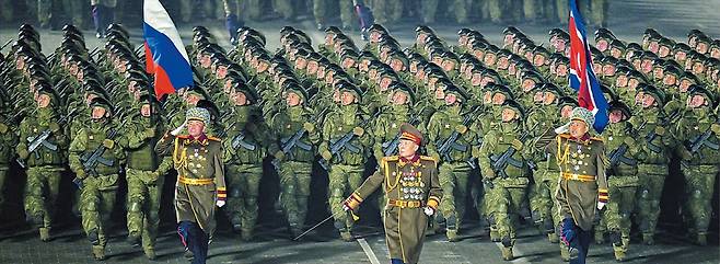 러시아 깃발 함께 들고 행진  북한 군인들이 25일 밤 평양 김일성광장에서 열린 노동당 제9차 대회 기념 열병식에서 행진을 하고 있다. 지난 19일 개막한 9차 당 대회는 당 대회 결정서를 채택하고 김정은 북한 국무위원장의 폐회사를 끝으로 이날 종료했다./노동신문 뉴스1