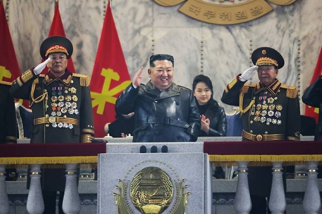 김정은·주애 부녀 ‘판박이 가죽 패션’ - 김정은 북한 국무위원장이 지난 25일 제9차 노동당 대회를 기념하는 열병식에서 거수경례를 하고 있다. 뒤쪽에는 김 위원장과 마찬가지로 검은 가죽 외투 차림을 한 김 위원장의 딸 주애가 자리에 앉아 박수를 치고 있다. 노동신문은 26일 열병식 소식과 함께 이 사진을 공개했다. 왼쪽부터 노광철 국방상, 김 위원장, 리영길 인민군 총참모부 총참모장. 평양 노동신문 뉴스1