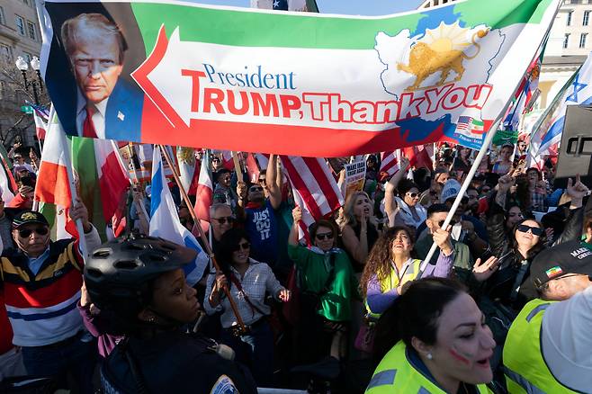 People who support the U.S. and Israel strikes on Iran, hold a banner with a photo of President Donald Trump during a rally near the White House, Saturday Feb. 28, 2026, in Washington. (AP Photo/Jose Luis Magana)<저작권자(c) 연합뉴스, 무단 전재-재배포, AI 학습 및 활용 금지>