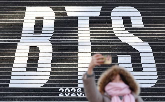 서울 종로구 세종문화회관 계단에 설치된 방탄소년단(BTS)의 정규 5집 컴백을 알리는 홍보물을 배경으로 관광객들이 기념촬영을 하고 있다. 뉴스1