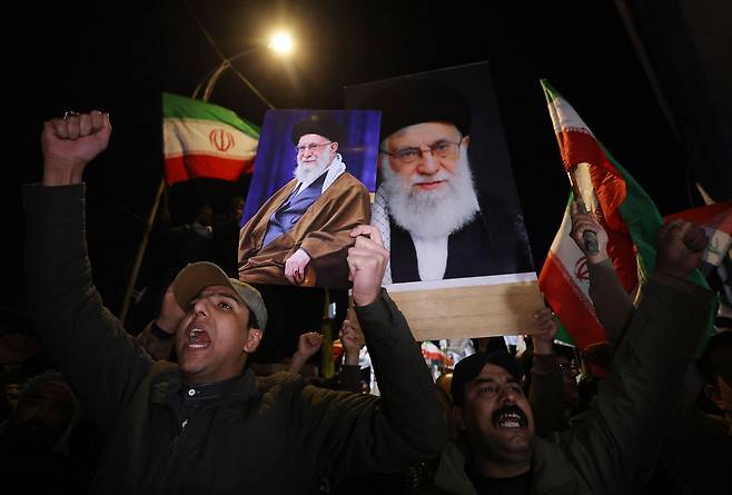 현지시간 28일 이라크 바그다드에 위치한 미국 대사관이 위치한 그린 존으로 통하는 다리 위에서 이라크 시아파 주민들이 미국의 이란 공격과 이스라엘의 이란 공격에 반대하는 시위를 벌이며 이란 최고 지도자 아야톨라 알리 하메네이의 초상화를 들고 이란 국기를 흔들며 구호를 외치고 있다. AFP=연합뉴스