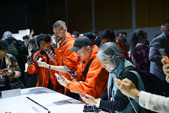 주황색 잠바를 입은 '미팬'(샤오미 단골 고객)들이 지난달 28일(현지시간) 스페인 바르셀로나에서 열린 글로벌 론칭 행사 후 체험존에서 샤오미17 시리즈를 살펴보고 있다. 사진 샤오미