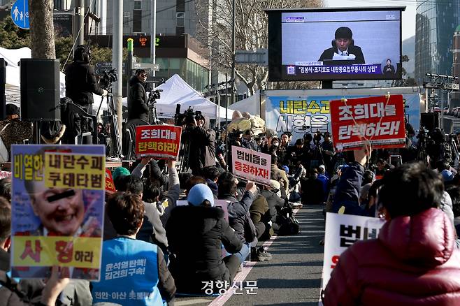 지난 2월 19일 서울 서초구 서울중앙지법 앞에서 시민들이 윤석열 전 대통령과 법원을 비판하는 피켓을 든 채 내란 사건 1심 선고 방송을 시청하고 있다. 문재원 기자