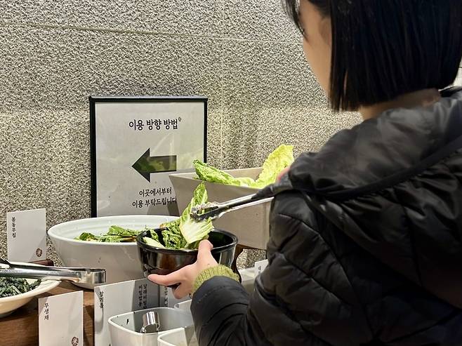 이랜드이츠가 운영하는 한식 뷔페 자연별곡에서 한 손님이 봄동을 담는 모습. [이랜드이츠 제공]