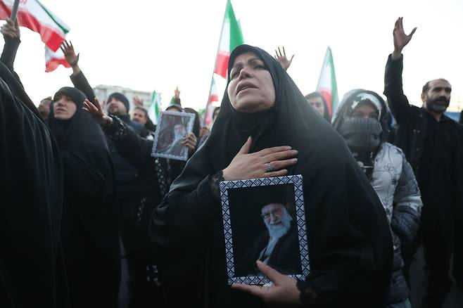 Mourners hold pictures of Iranian Supreme Leader Ayatollah Ali Khamenei following his death, at Enqelab Square in Tehran on March 1. [EPA/YONHAP]