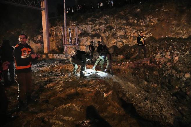 [예루살렘=AP/뉴시스] 1일(현지 시간) 이스라엘 예루살렘에서 보안 요원들이 이란에서 발사한 미사일 공습으로 파손된 도로를 살펴보고 있다. 2026.03.02.