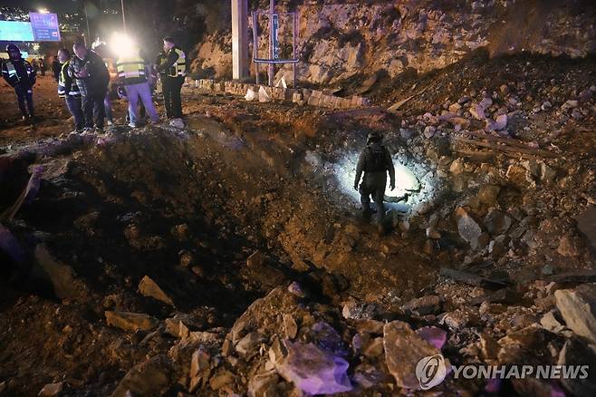 이란 미사일에 팬 예루살렘 도로 (예루살렘 AP=연합뉴스) 2026년 3월 1일 이란이 발사한 미사일로 예루살렘의 도로가 움푹 팬 현장을 이스라엘 보안부대가 살펴보고 있다. (AP Photo/Mahmoud Illean) 2026.3.2.