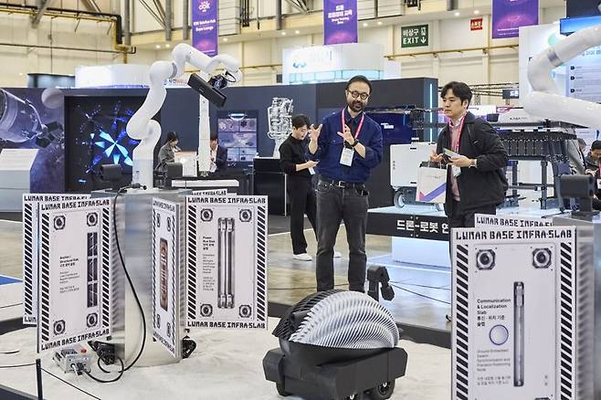 우주스타트업 베이스앤파워시티가 선보인 달에 기지를 건설하는 '달 탐사 로보'(가운데 둥근 기계) 모습. 뒤편으로는 달 기지 건설 로봇팔이 보인다. 벡스코 제공