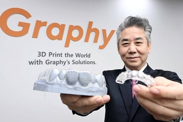 심운섭 그래피 대표이사가 서울 금천구 그래피 본사에서 왼손에 형상기억 투명교정장치를, 오른손에 자체 개발한 레진으로 만든 치아 모형을 들고 소개하고 있다. 조태형 기자