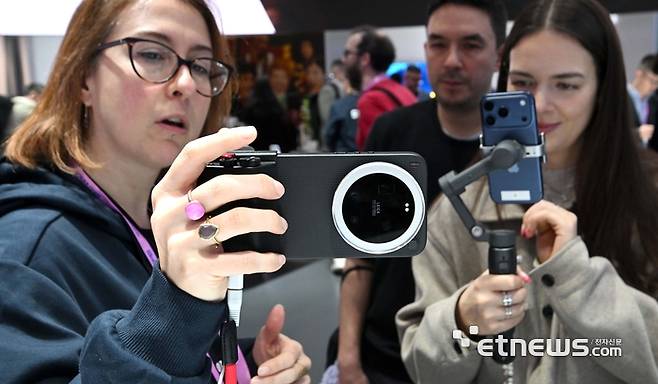 MWC26 개막 이튿날인 3일(현지시간) 샤오미 부스에서 관람객이 포토그래프 키트를 장착한 샤오미17 울트라 제품을 살펴보고 있다.