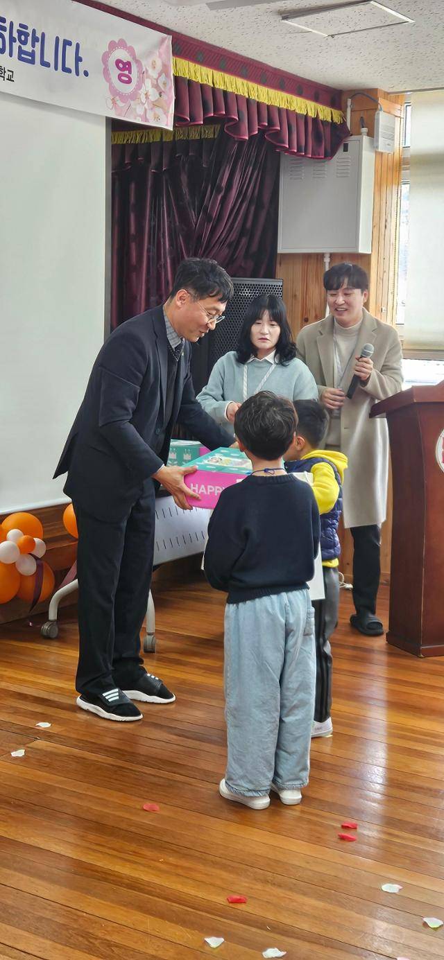 3일 경남 통영시 욕지초등학교에서 최국남(왼쪽) 교장이 신입생들에게 선물 꾸러미를 전달하고 있다. 통영=박은경 기자