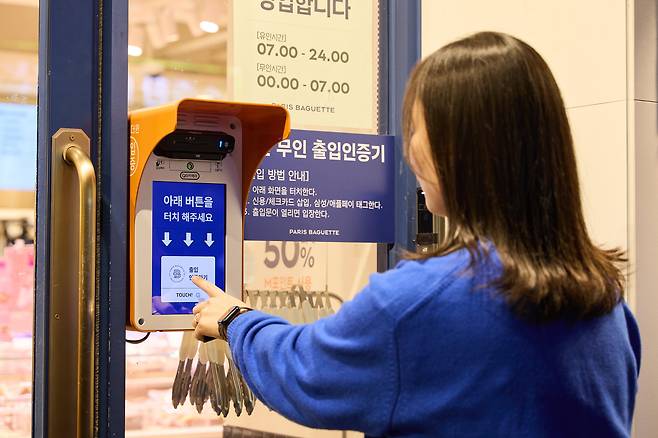24시 운영되는 파리바게뜨의 하이브리드 매장 앞에서 손님이 출입 인증을 하고 있다. 카드를 통해 인증해야 무인 운영하는 야간에 들어갈 수 있는 구조다. / 파리바게뜨